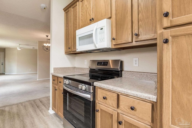 6027 Dallas Ave, Pensacola, FL 32526 - kitchen featuring stainless steel range with electric stovetop, white microwave, light wood finished floors, and light countertops