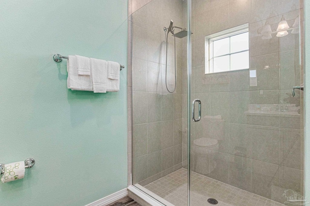 bathroom featuring a shower with shower door and toilet