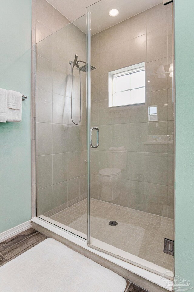 bathroom featuring toilet, wood-type flooring, and walk in shower