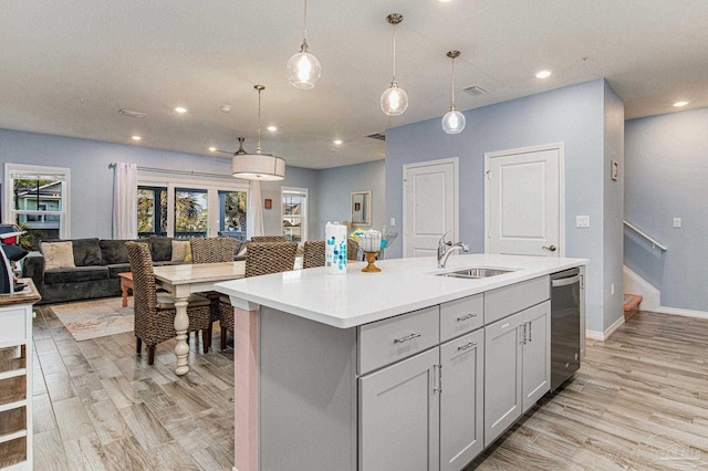 kitchen featuring light hardwood / wood-style flooring, dishwasher, a kitchen island with sink, gray cabinets, and sink