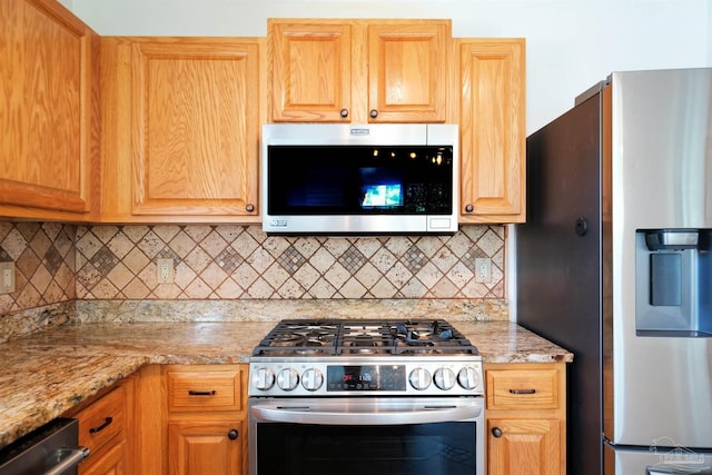 kitchen featuring light stone countertops, backsplash, and appliances with stainless steel finishes