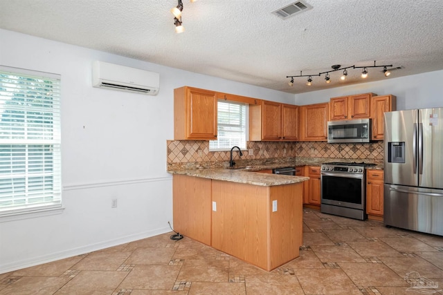 kitchen with decorative backsplash, kitchen peninsula, stainless steel appliances, sink, and a wall mounted AC