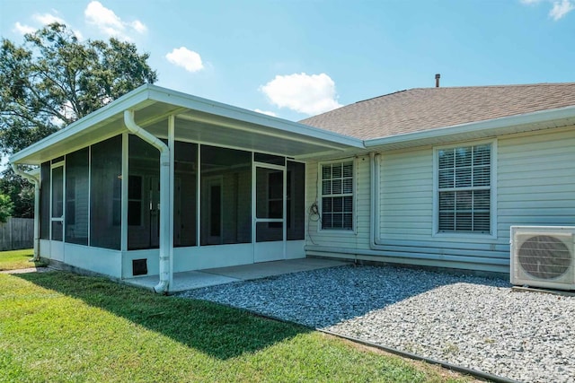 back of property with ac unit, a sunroom, and a yard