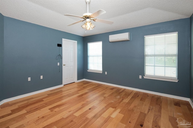 empty room with light wood-type flooring, a textured ceiling, and plenty of natural light