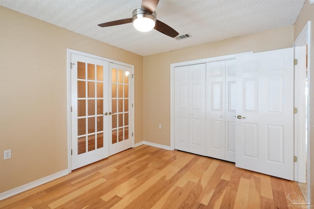 unfurnished bedroom with ceiling fan, french doors, a textured ceiling, a closet, and light wood-type flooring