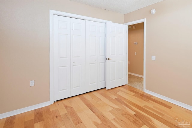 unfurnished bedroom with hardwood / wood-style flooring, a closet, and a textured ceiling