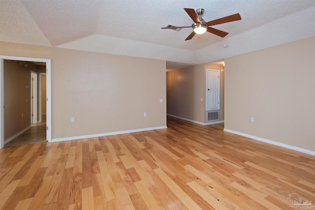 spare room featuring a textured ceiling, light hardwood / wood-style floors, lofted ceiling, and ceiling fan