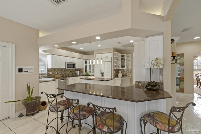 kitchen with light tile patterned floors, a peninsula, appliances with stainless steel finishes, and a breakfast bar area