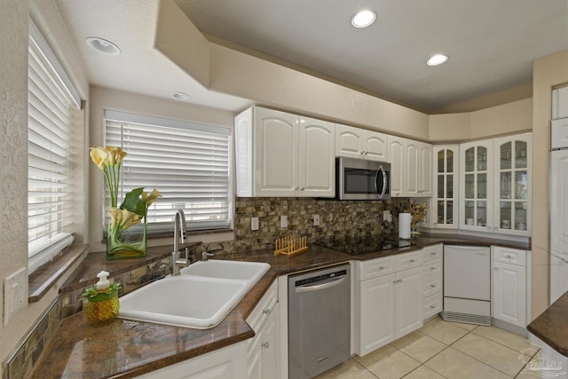 kitchen with dark countertops, white cabinets, stainless steel appliances, and a sink