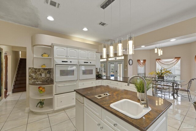 kitchen featuring a warming drawer, open shelves, a sink, and oven