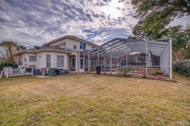 rear view of property with a yard, stucco siding, a pool, a patio area, and glass enclosure