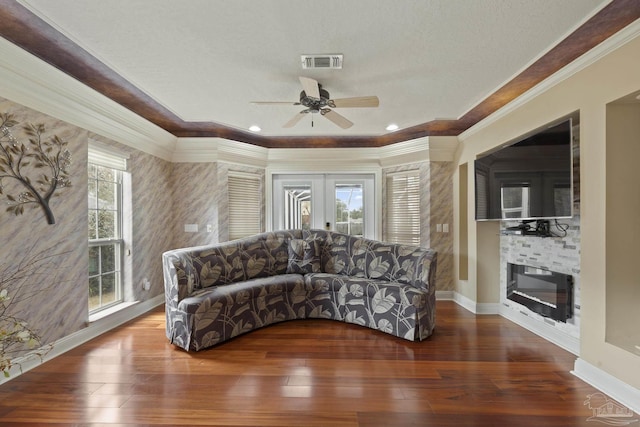 living room with wood-type flooring, visible vents, ornamental molding, and a glass covered fireplace