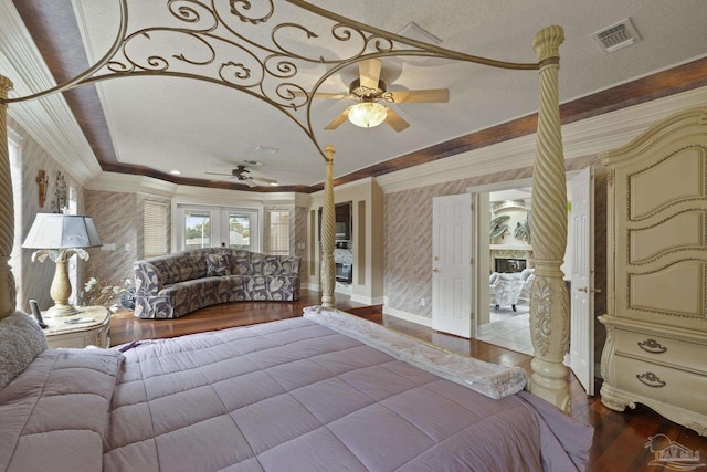 bedroom with crown molding, wood finished floors, visible vents, and wallpapered walls