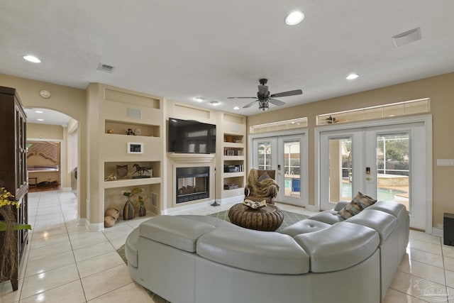 living area with light tile patterned floors, visible vents, arched walkways, french doors, and built in shelves