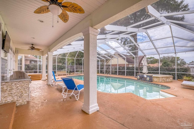 outdoor pool featuring glass enclosure, a patio area, fence, and an outdoor kitchen