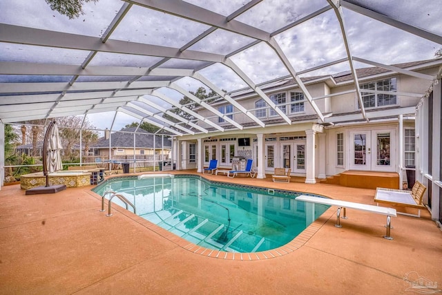 view of swimming pool with french doors, a pool with connected hot tub, glass enclosure, a patio area, and a diving board