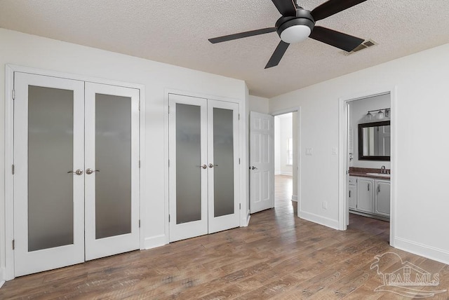 3117 Albert Ct, Pensacola, FL 32504 - unfurnished bedroom featuring multiple closets, wood finished floors, a textured ceiling, french doors, and ensuite bath