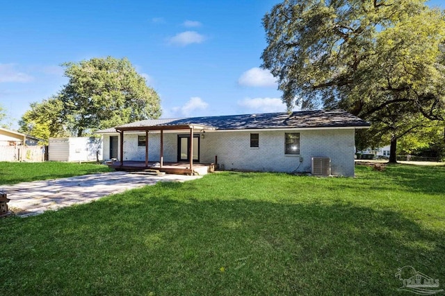 rear view of property featuring a lawn and cooling unit