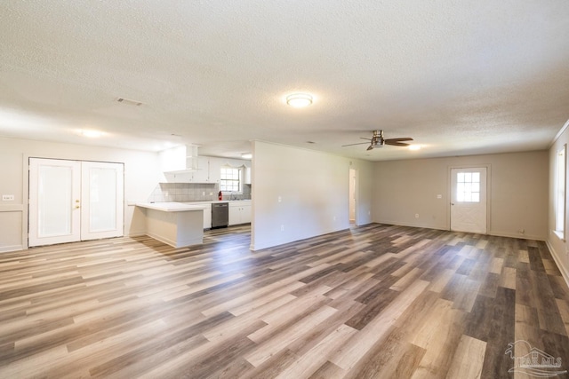 unfurnished living room featuring ceiling fan, light hardwood / wood-style floors, and a textured ceiling