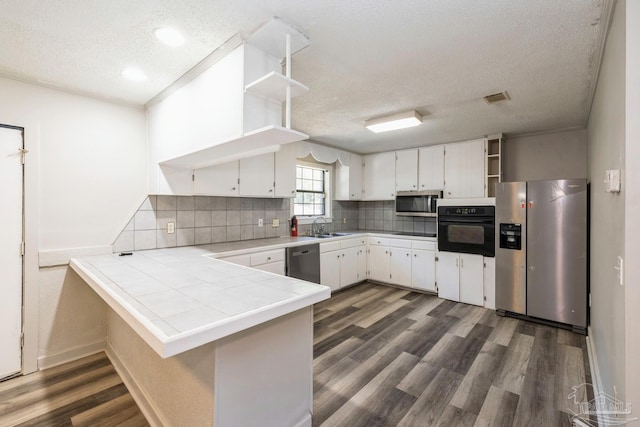 kitchen with white cabinetry, sink, dark hardwood / wood-style floors, kitchen peninsula, and appliances with stainless steel finishes