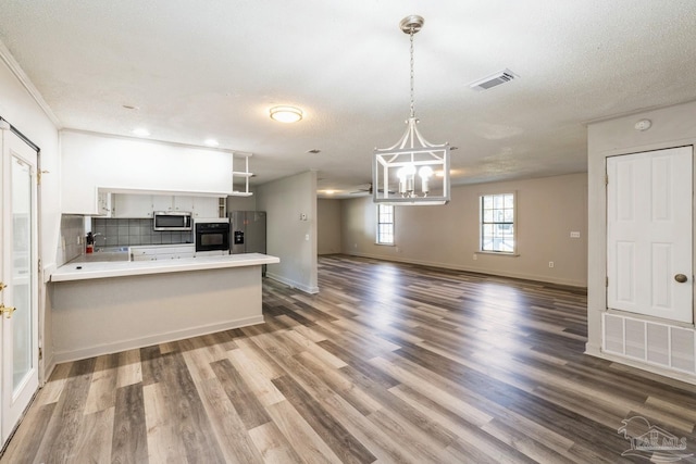 kitchen with hardwood / wood-style floors, backsplash, white cabinets, and stainless steel appliances