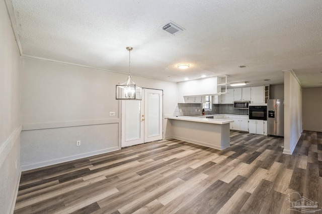 kitchen with dark wood-type flooring, kitchen peninsula, a textured ceiling, white cabinets, and appliances with stainless steel finishes