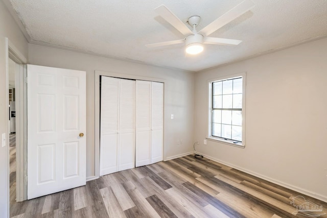 unfurnished bedroom with ceiling fan, a closet, wood-type flooring, and a textured ceiling