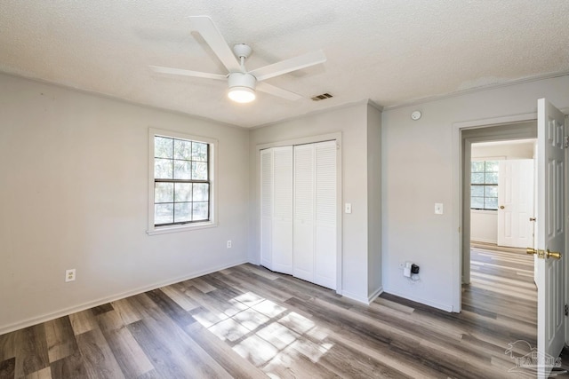 unfurnished bedroom featuring ceiling fan, wood-type flooring, and multiple windows