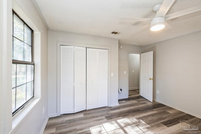 unfurnished bedroom featuring ceiling fan, a closet, a textured ceiling, and hardwood / wood-style flooring