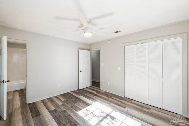 unfurnished bedroom with ceiling fan, a closet, and wood-type flooring