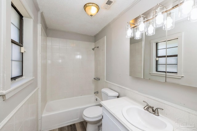 full bathroom with wood-type flooring, a textured ceiling, toilet, vanity, and tiled shower / bath