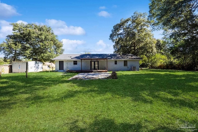 rear view of house with a lawn, a patio area, and a shed