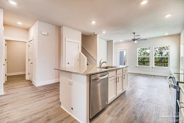 kitchen with white cabinets, light wood-type flooring, stainless steel appliances, and an island with sink