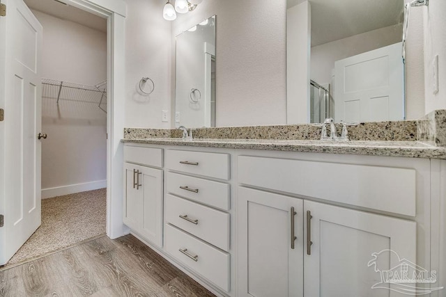 bathroom with wood-type flooring, vanity, and an enclosed shower