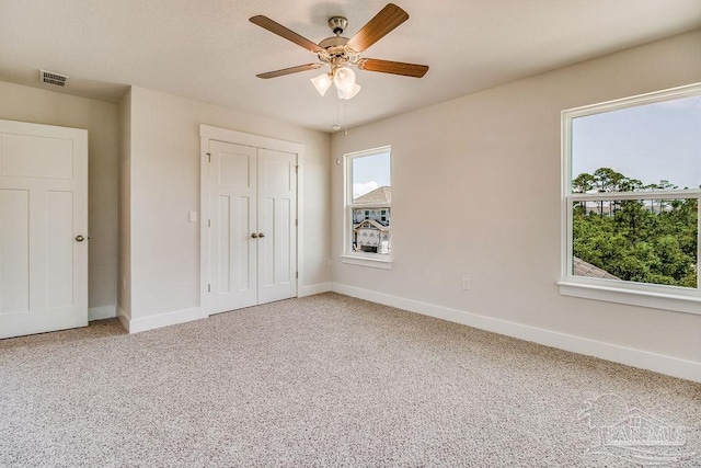 unfurnished bedroom featuring carpet floors, a closet, and ceiling fan