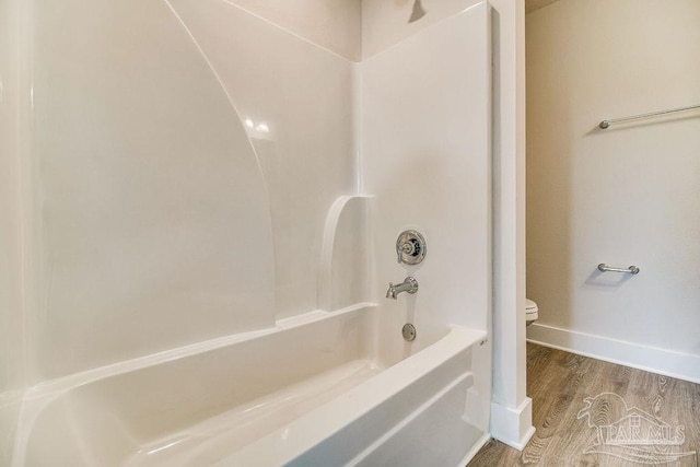 bathroom with bathtub / shower combination, hardwood / wood-style floors, and toilet