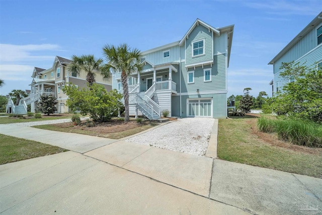 coastal inspired home with a porch, driveway, and stairway