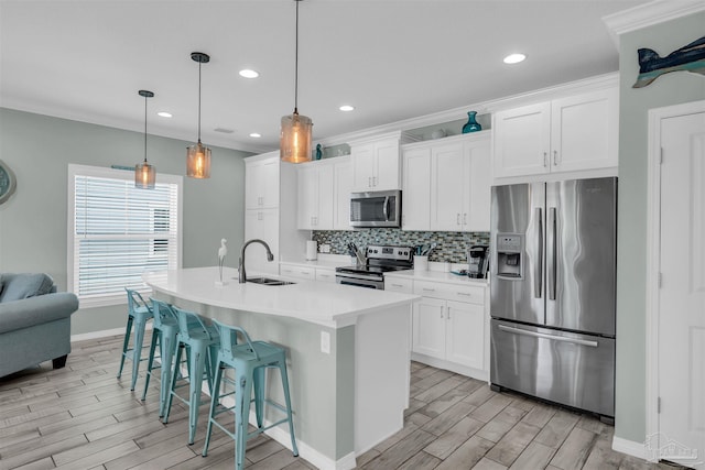kitchen featuring an island with sink, a breakfast bar area, appliances with stainless steel finishes, a sink, and wood finish floors