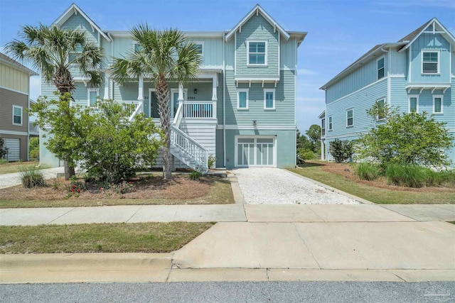 coastal home featuring covered porch, driveway, and stairs