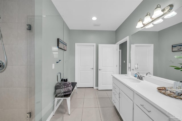 full bath featuring tiled shower, tile patterned flooring, vanity, baseboards, and visible vents