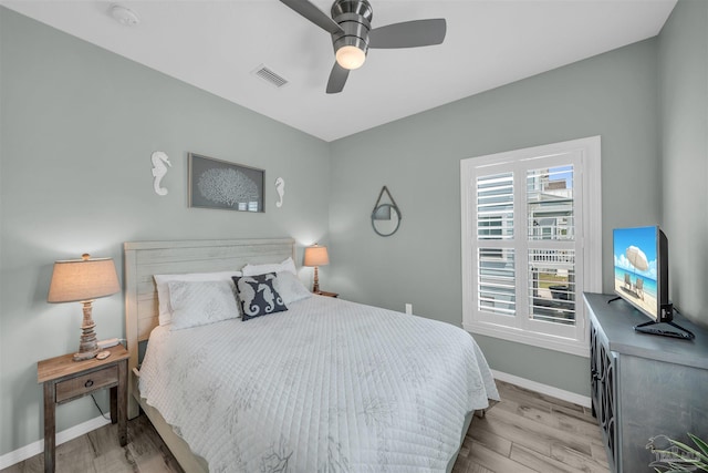 bedroom featuring baseboards, visible vents, wood finished floors, and ceiling fan