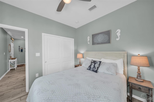 bedroom with a closet, a ceiling fan, visible vents, baseboards, and wood finished floors