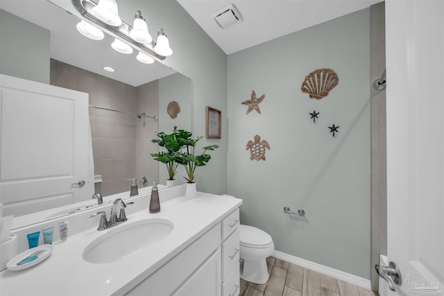 full bathroom featuring tiled shower, toilet, vanity, baseboards, and visible vents