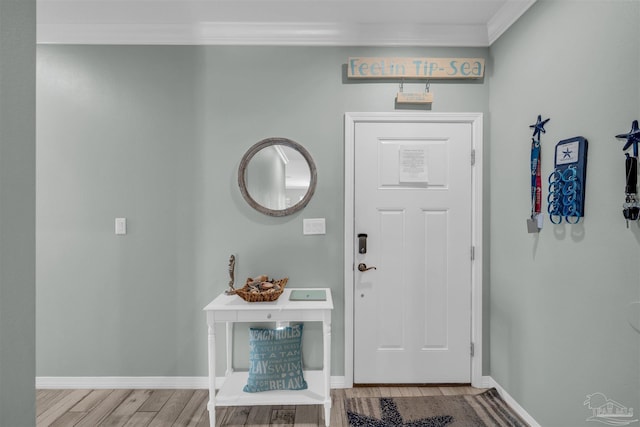 entryway with wood finished floors, crown molding, and baseboards