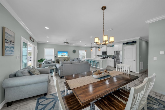 dining space with recessed lighting, light wood-type flooring, baseboards, ornamental molding, and ceiling fan with notable chandelier