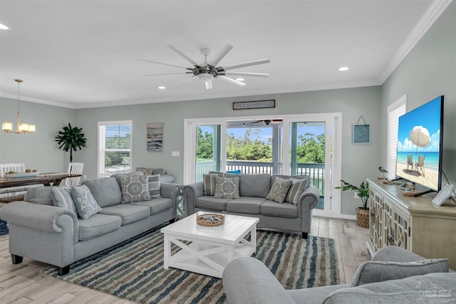 living area with wood finished floors, recessed lighting, ornamental molding, and ceiling fan with notable chandelier