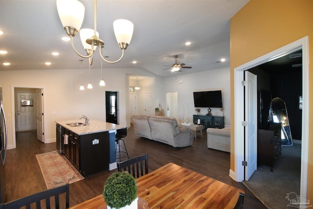 dining area featuring vaulted ceiling, sink, dark hardwood / wood-style floors, and ceiling fan with notable chandelier