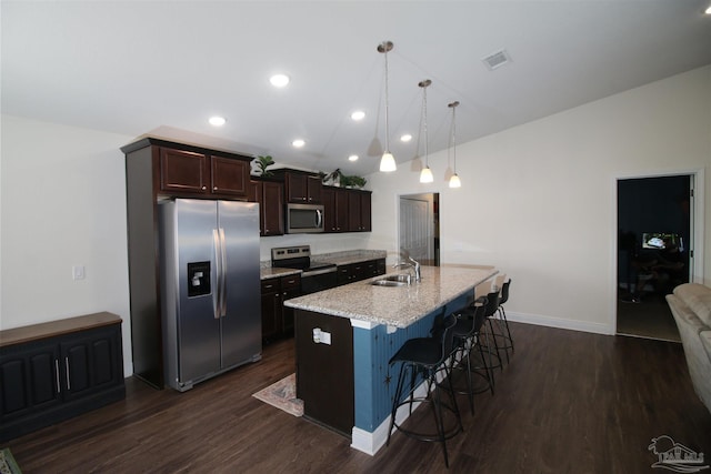 kitchen featuring stainless steel appliances, sink, pendant lighting, a breakfast bar area, and an island with sink