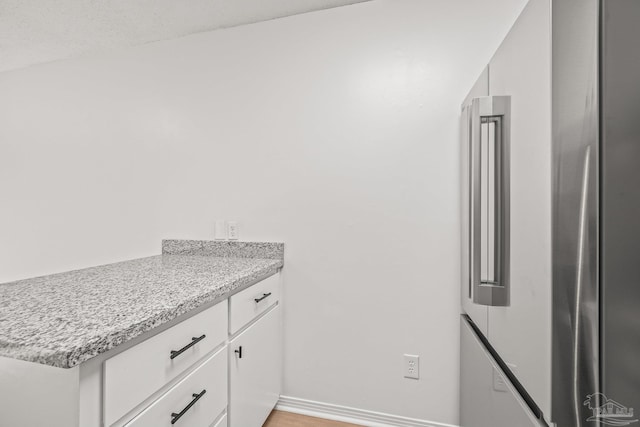 kitchen featuring white cabinets and light stone countertops