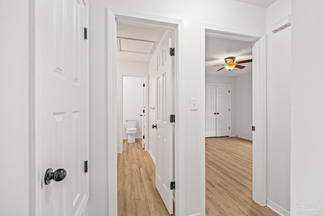 corridor with light wood-type flooring and a textured ceiling